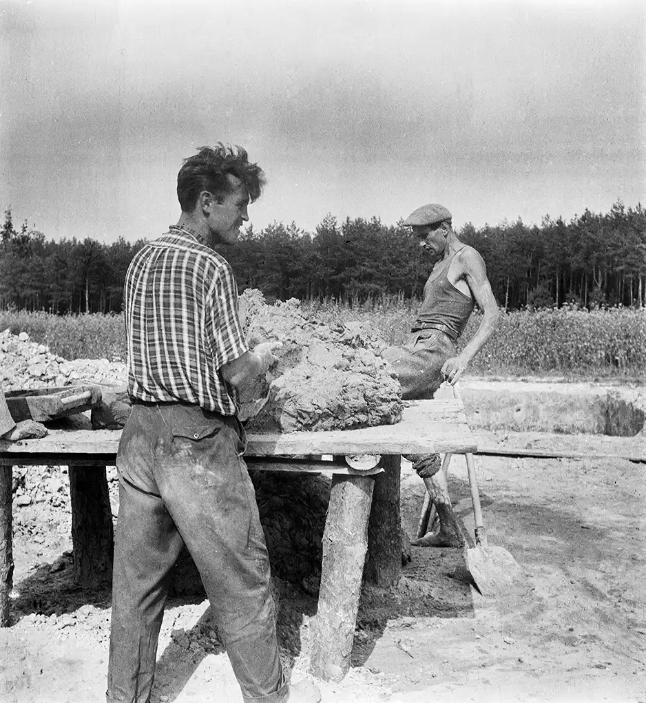 dwaj mężczyźni na placu budowy przy stole, wyrabiający glinę