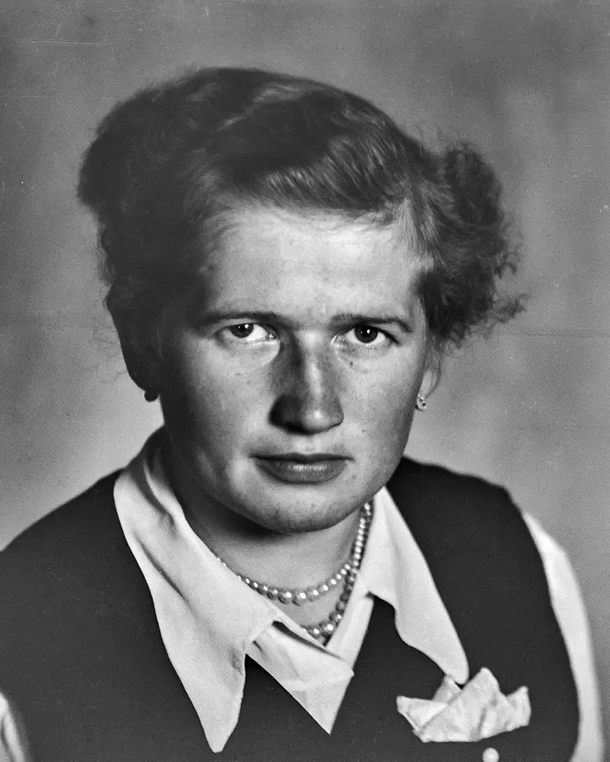 młoda kobieta w eleganckiej białej bluzce i perłach siedząca w kamizelce, portret studyjny