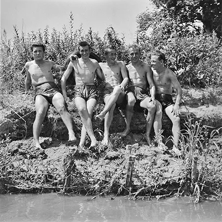 pięciu mężczyzn w kąpielówkach siedzących na skarpie rzecznej