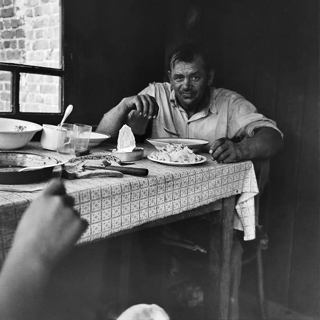 mężczyzna jedzący zupę, siedzący przy stole we wnętrzu